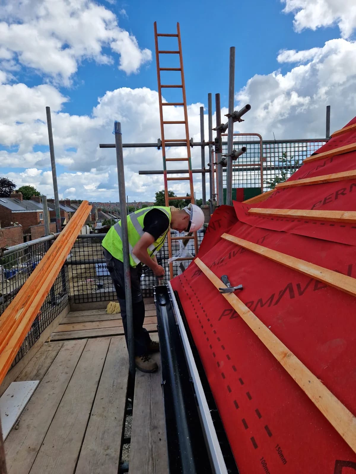 A roofer working on a roof in breather membrane and battens during a repair